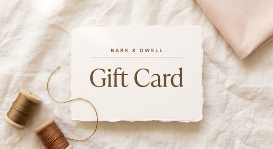 Bark and Dwell gift card design on cream deckled cotton card stock, with wooden spools of embroidery thread and blush canvas on linen