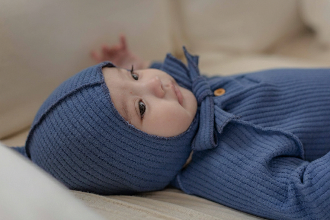 Baby lying down wearing the navy waffle knit bonnet tied under the chin