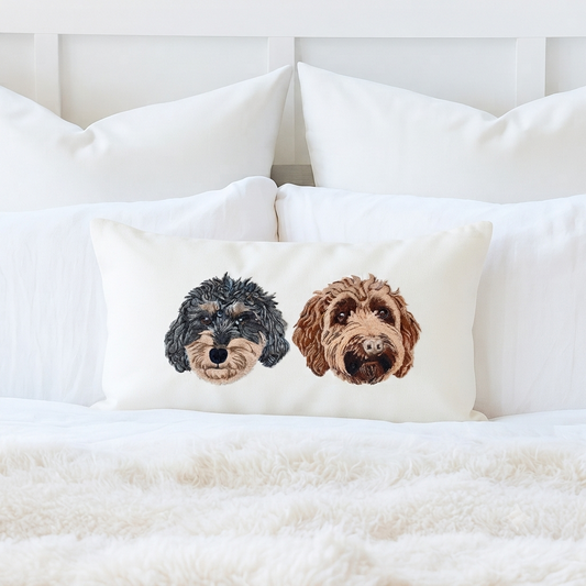 Cream 12 by 20 lumbar pillow cover on a white bed, embroidered with two doodle portraits, one black and one apricot